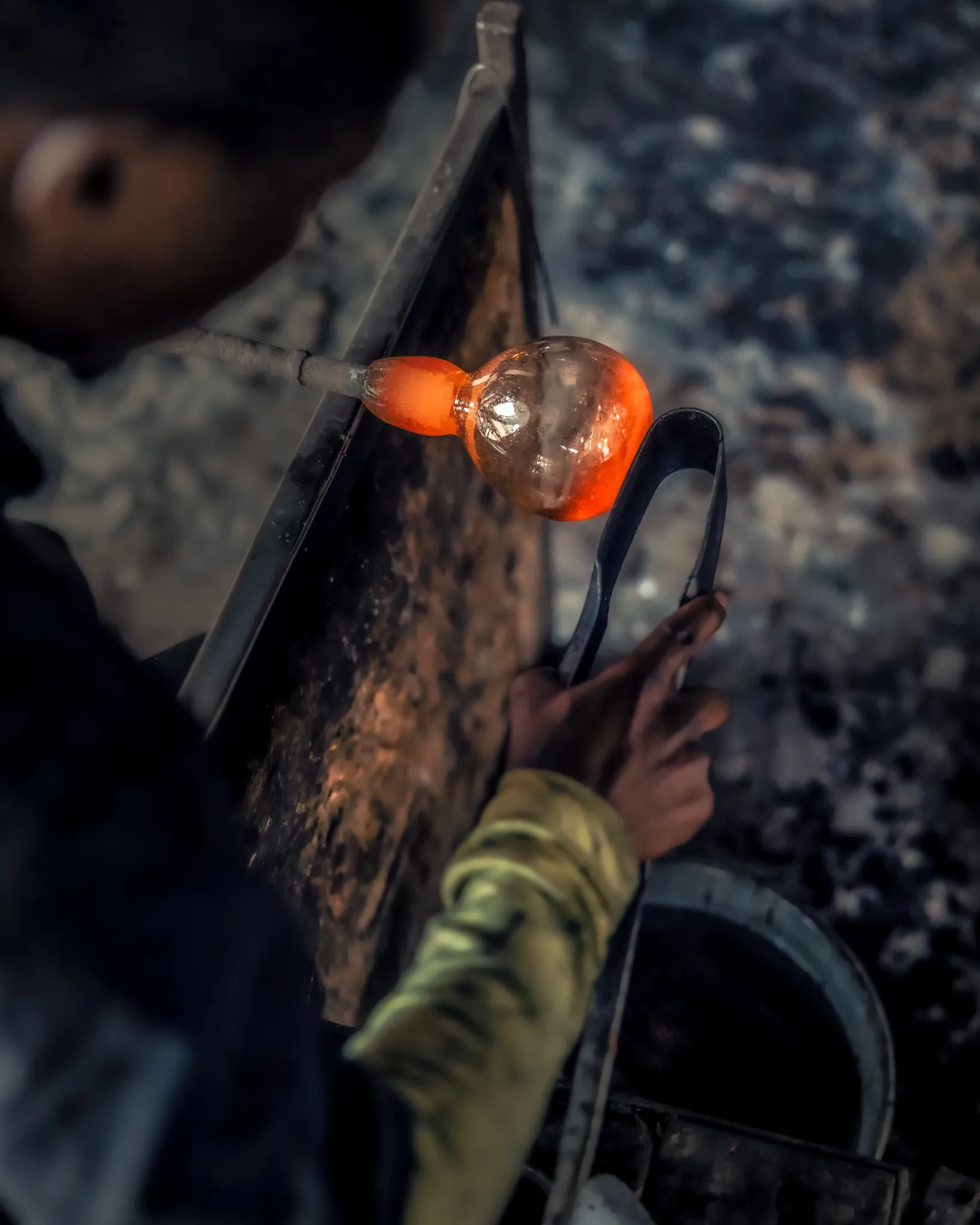 A Shanga craftsman shaping molten glass from recycled bottles at the furnace — Photo: Elewana Collection