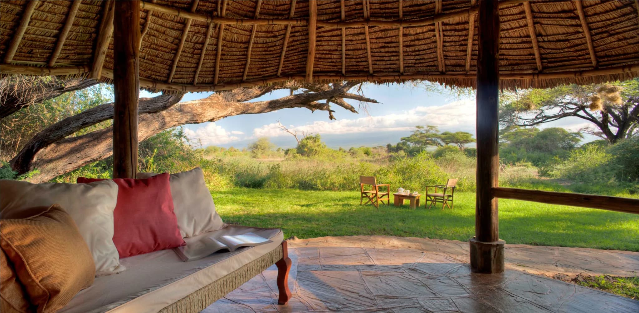 A thatched private veranda at Tortilis Camp, framing the Amboseli bush and an acacia — Photo: Elewana Collection