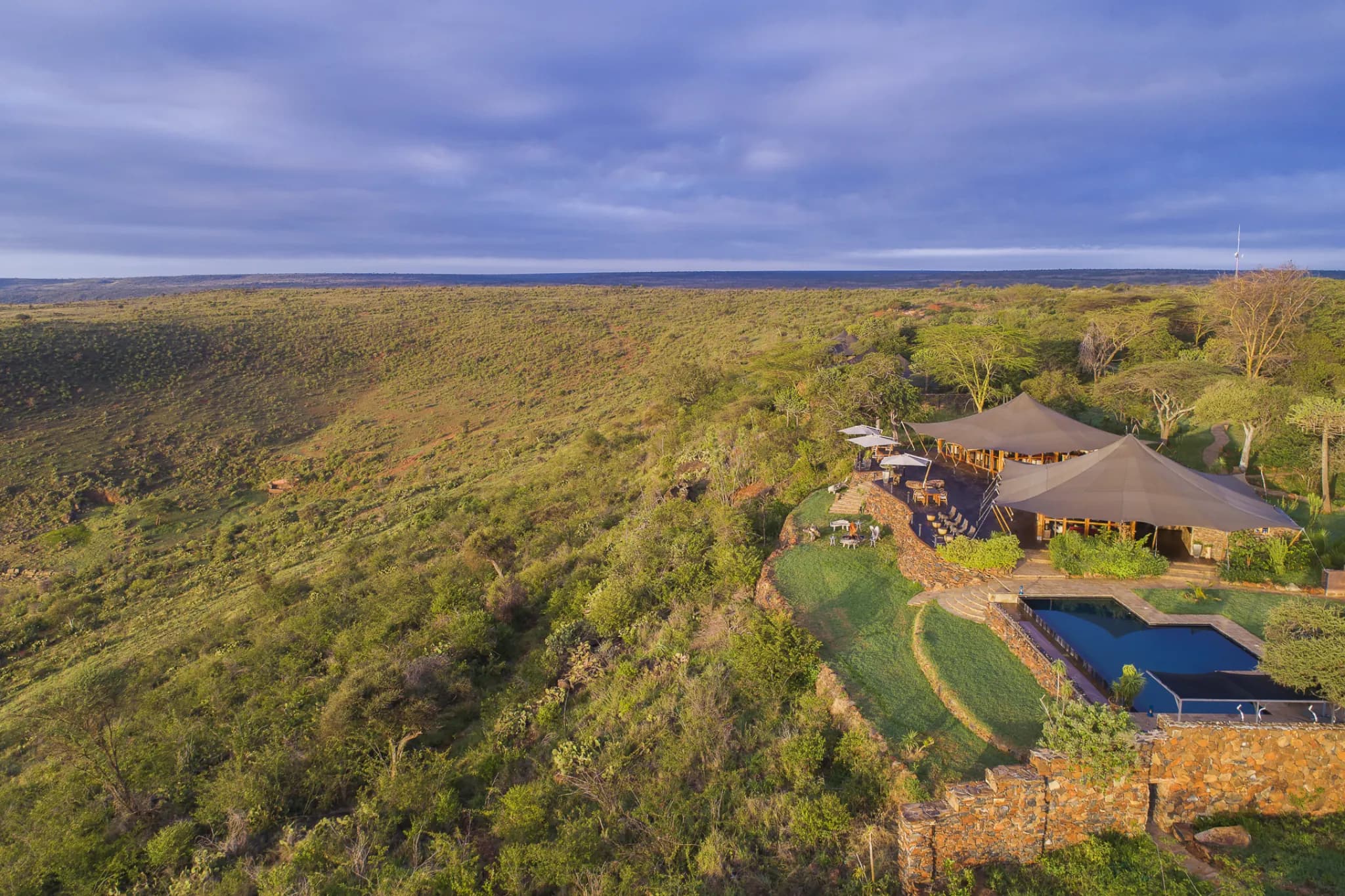 Aerial view of a tented camp on the edge of the Loisaba escarpment, looking out across the Laikipia wilderness toward Mount Kenya